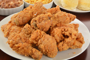 A plate of delicious friend chicken with side dishes in the background.